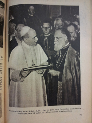 Bishop Raible hands an album of mission work to the Pope